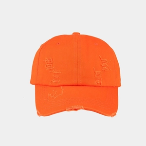 Close-up of orange washed cotton baseball cap featuring vintage distressed torn details