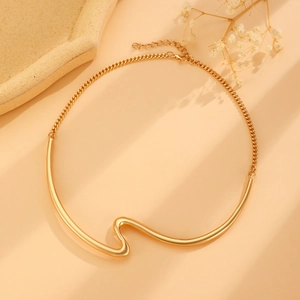 Flat lay of gold geometric wave collar necklace with minimalist lighting and shadows