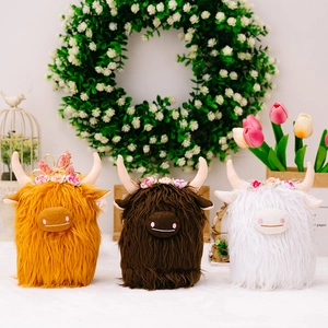 Three plush Highland cows in ginger, brown, and white with floral crowns and soft fur