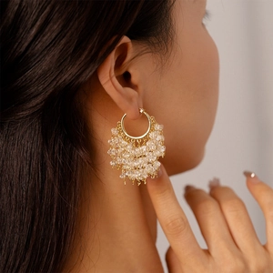 Macro detail of 18k gold plated star earrings with crystal tassels on a female model