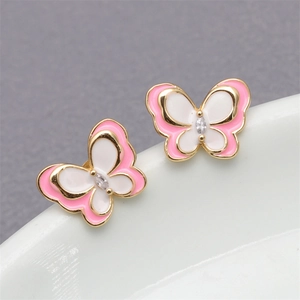 Macro shot of gold butterfly earrings with pink and white enamel and clear crystal center
