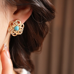 Macro shot of gold filigree flower earring with turquoise stone and sparkling crystals
