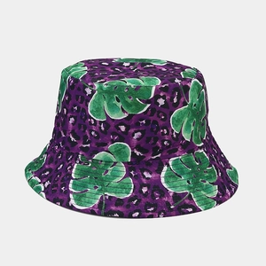 Dettaglio del cappello da pescatore leopardato viola con foglie di monstera verdi tropicali