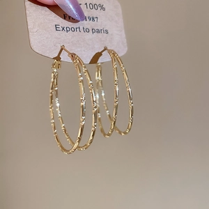 Detail shot of golden double-layer hoop earrings with textured bamboo patterns and shiny finish