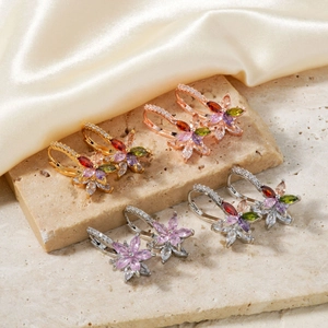 Elegant lotus flower zircon earrings in gold and silver finishes on a beige stone surface