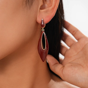 Close-up of model wearing burgundy enamel teardrop earrings with gold metallic frame