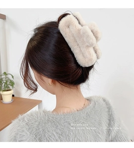 Close-up of a plush cream faux fur claw clip styled on a woman's hair for autumn winter