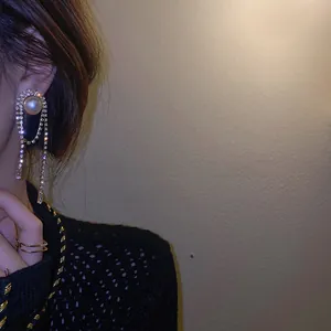 Detail of elegant long tassel earrings with white pearls and sparkling rhinestone fringes