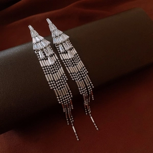 Detail of silver tassel earrings with geometric rhinestones on a brown display