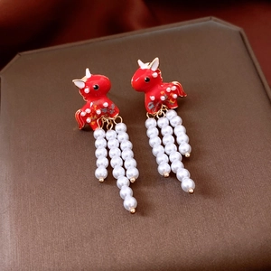 Detail of red enamel horse earrings with elegant hanging white pearl tassels