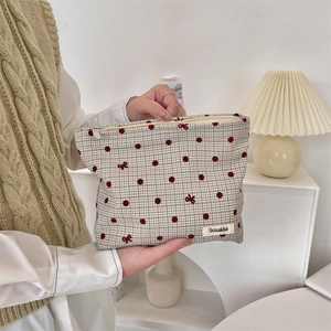 Dettaglio della trousse in tela a quadretti verdi con motivi di pois e fiocchi rossi