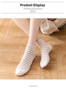 Detailed close-up of cream crew socks with brown stripes and ribbed cuffs on a model