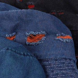 Distressed blue denim bucket hat featuring vibrant orange ripped holes and frayed details