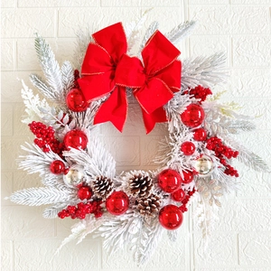 Detail of frosted Christmas wreath with red velvet bow, silver balls and pine cones