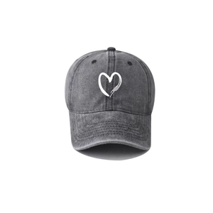 Close-up of dark grey washed denim baseball cap with white hand-drawn heart embroidery