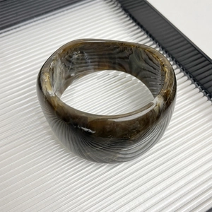Detailed view of wide resin bangle with brown marble texture and amber gradient finish