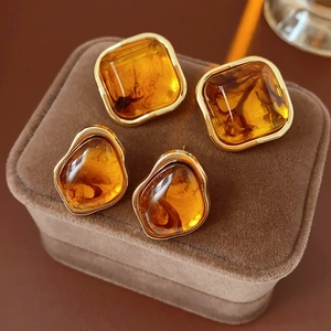 Detailed close-up of vintage geometric gold earrings with amber resin on velvet case