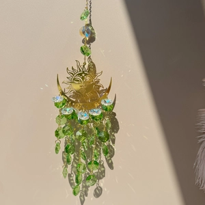 Macro shot of sun and moon metal wind chime featuring green and iridescent crystal beads