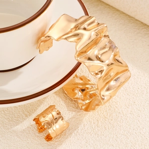Close-up of golden irregular textured leaf cuff bracelet and matching ring set