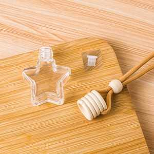 Star-shaped glass perfume bottle with wooden cap and hanging rope on a wooden board