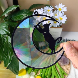 Detailed close-up of rainbow holographic crescent moon and black cat suncatcher charm