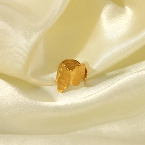 Detailed close-up of golden irregular lava texture ring on beige silk background fabric
