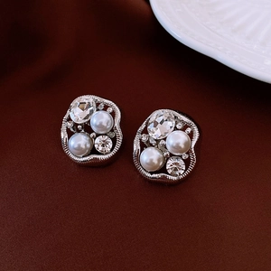 Detail of irregular silver earrings with pearls and crystals on dark velvet fabric