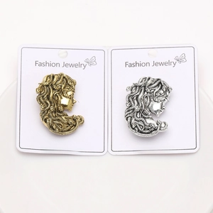 Detailed view of vintage Medusa head brooches in gold and silver finish on display cards