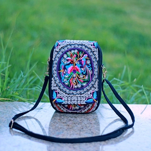 Detail of ethnic embroidered crossbody bag with floral patterns on stone surface