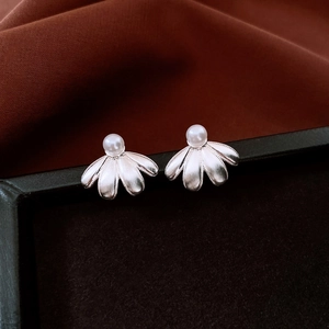 Macro detail of silver ginkgo leaf earrings with pearl inlay and brushed metal texture