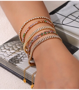 Close-up of five gold-plated tennis bracelets with colorful zircons and adjustable chains