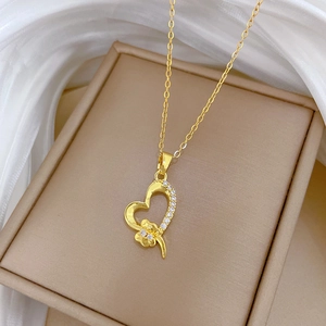 Macro shot of gold heart necklace with rhinestones and flower detail on beige tray