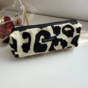 Detalle del estuche de lona con estampado de vaca en blanco y negro y cierre de cremallera