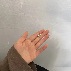 Detailed close-up of S-shaped silver stud earrings on palm for size reference