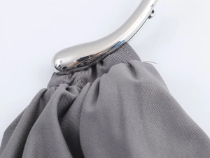 Detailed view of grey pleated fabric texture and silver metal curved handle on a handbag