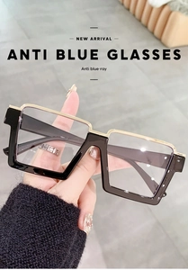 Detailed shot of black and gold square anti-blue light glasses held by a hand