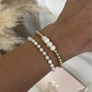 Golden beaded bracelet set with natural freshwater pearls on a woman's wrist