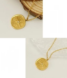Detail of gold starburst compass pendant in polished stainless steel with zircon inlay