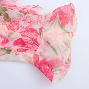Macro detail of pink floral chiffon fabric featuring elegant ruffled layers and edges