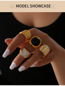 Detailed view of four gold-plated rings set with black agate stones and micro-pave zircons
