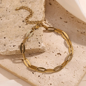 Close-up of 14K gold plated lip chain anklet with lobster clasp on beige textured stone