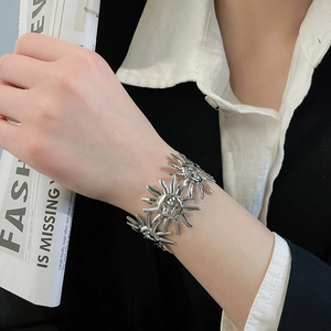 Detailansicht eines silbernen Vintage-Armreifs mit Sonnenmotiven am Damenhandgelenk