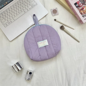 Close-up of a purple quilted makeup pouch with a top zipper and a side carry handle