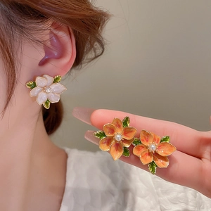 Detail of vintage flower earrings with enamel petals and pearl center on ear