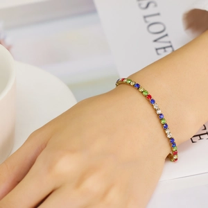 Detail shot of a bohemian gold tennis bracelet with colorful zircon stones on wrist