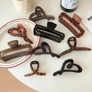 Flat lay of acetate claw clips in tortoiseshell and black patterns on a white table