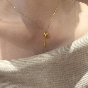 Macro shot of a 24K gold plated rocking horse pendant on a necklace worn on a collarbone