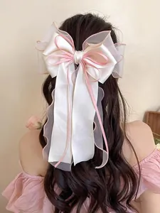 Close-up of a large white mesh bow hair clip with pink edges on wavy hair