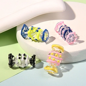 Close-up of colorful candy-shaped glass beads with dots and stripes on a textured platform