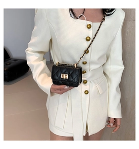 Close-up of a mini black quilted crossbody bag with gold chain and turn-lock clasp